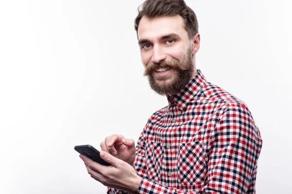 Glimlachend bebaarde man die zich voordeed tijdens het typen bericht op telefoon — Stockfoto