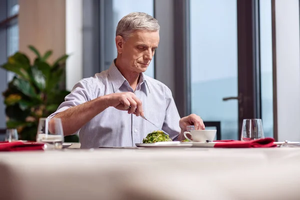 Konzentrierter reifer Mann isst Salat — Stockfoto
