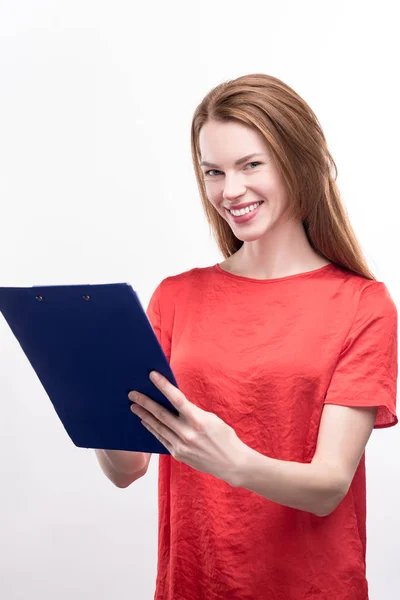 Pleasant ginger-haired woman making notes on sheet holder — Stock Photo, Image