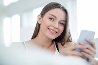 Telefonunu kullanan neşeli uzun saçlı kadın