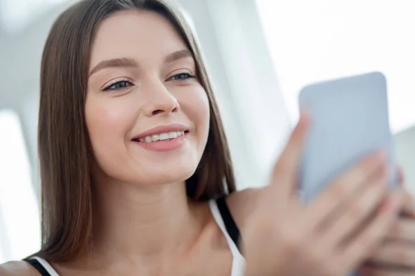 Vrolijke langharige jonge vrouw met behulp van haar telefoon — Stockfoto