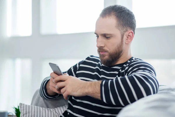 Ernsthafter junger Mann tippt auf seinem Handy — Stockfoto