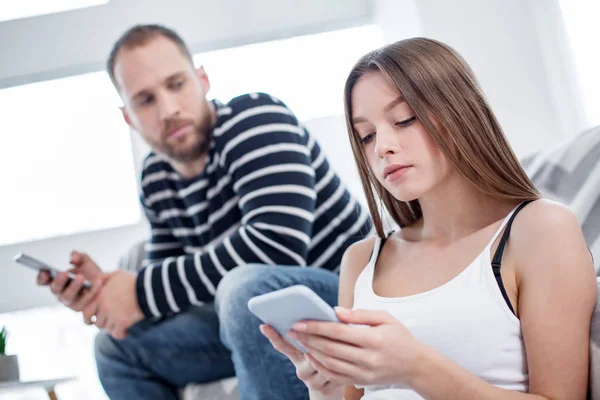 Serious young woman typing on her phone