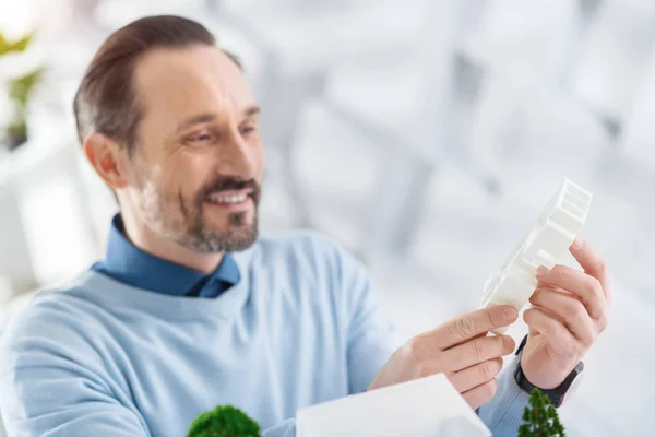 Счастливый инженер держит в руках модель будущего дома — стоковое фото