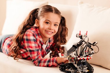 Beautiful preteen child beaming while playing with robot toy clipart