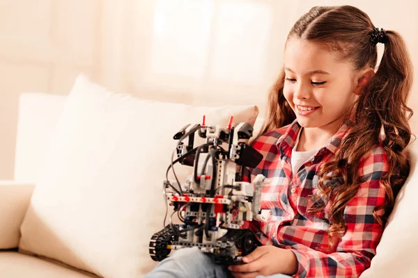 Adorabile ragazza con code di cavallo esaminando robot a casa — Foto Stock