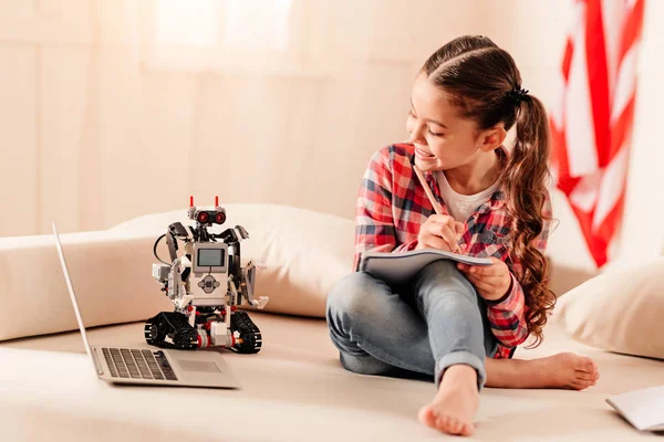 Smart child writing her essay on robotic machines
