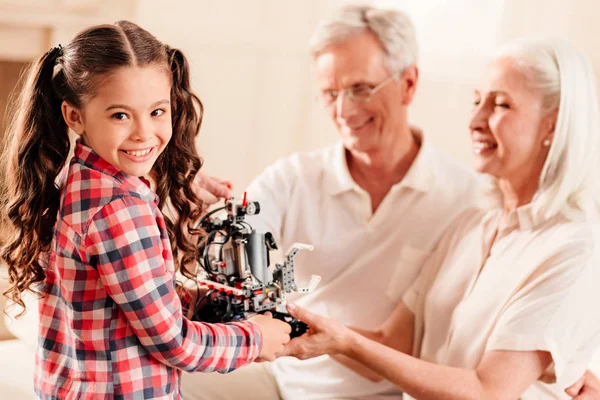Bedårande liten flicka visar hennes morföräldrar robot leksak — Stockfoto