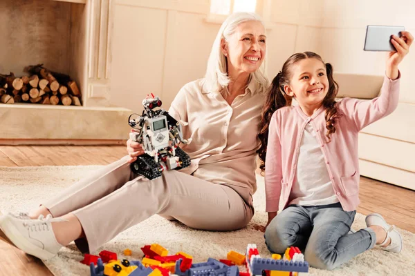 Niña inteligente tomando selfie con la abuela radiante —  Fotos de Stock