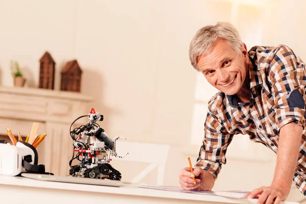 Радостный мужчина-инженер работает над новым роботом — стоковое фото