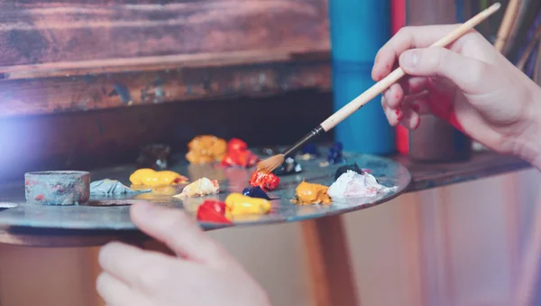 Plan intensifié de la main de l'enfant mélangeant des peintures colorées — Photo