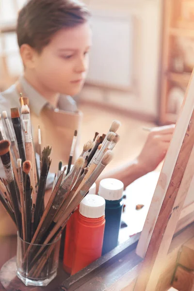 Серйозний хлопчик-підліток малює шедевр в студії — стокове фото