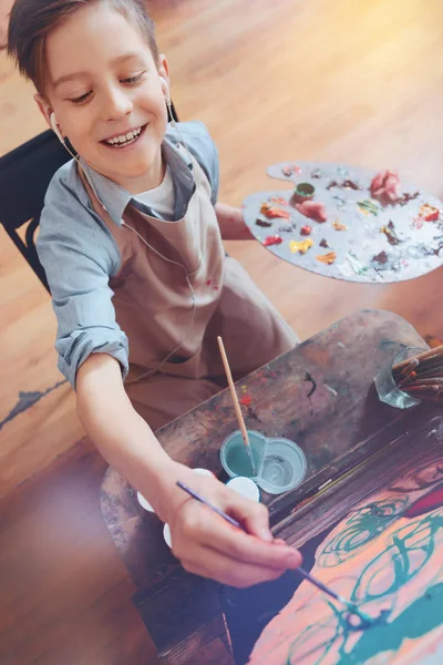 Beaming schoolboy paining masterpiece on art canvas