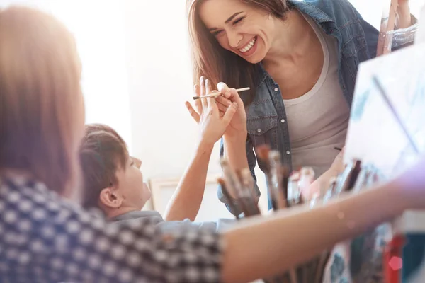 Divertida pintora bromeando con los niños en el estudio de pintura — Foto de Stock