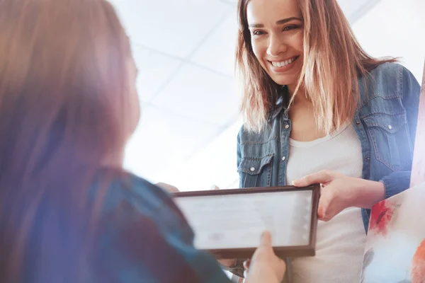 Cheerful teacher giving certificate to young lady after painting courses