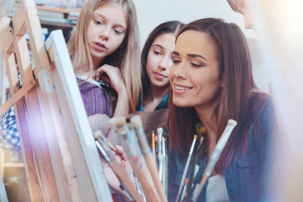 Crianças talentosas olhando para seu professor de pintura de trabalho — Fotografia de Stock
