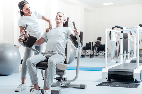 Alert old man exercising on a training device