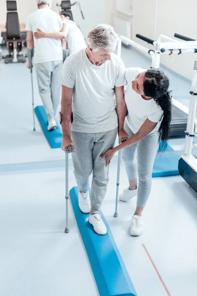 Hombre serio y anciano con sus bastones y su entrenador —  Fotos de Stock