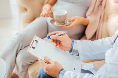 Bir doktor randevu sırasında notlar alarak yakın çekim