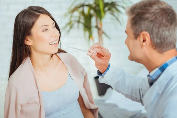 Male doctor checking throat of expectant mother — Stock Photo, Image