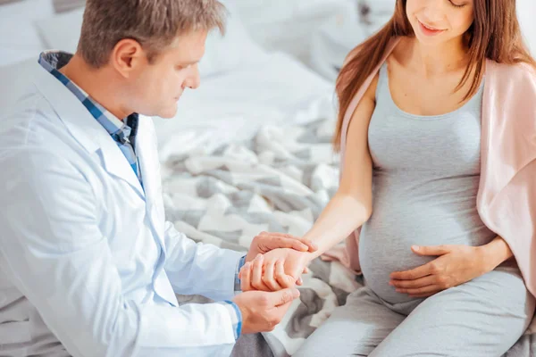 Médico sério verificando pulso de mulher grávida — Fotografia de Stock
