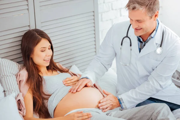 Amistoso médico chequeando protuberancia de la mujer embarazada — Foto de Stock