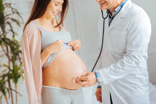 Médico sorridente ouvindo batimentos cardíacos de bebê — Fotografia de Stock