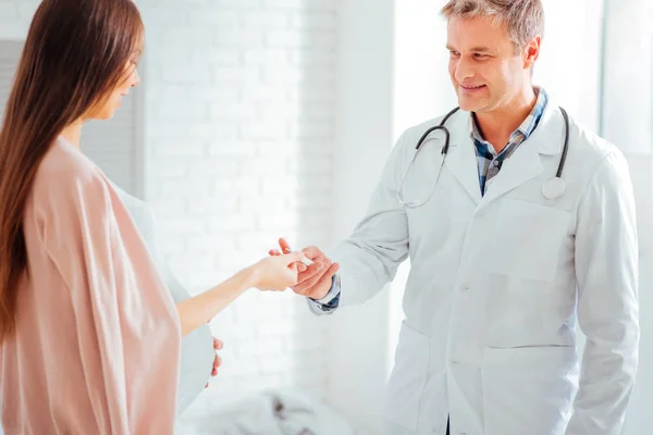 Cheerful doctor giving thermometer to pregnant woman — Stock Photo, Image