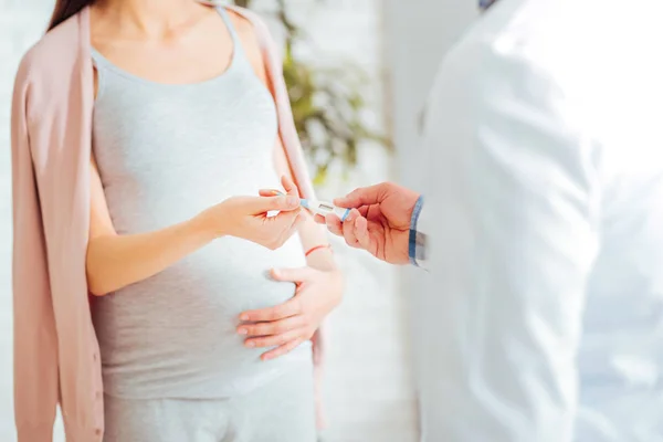 Scaled up look on expectant mother giving doctor thermometer — Stock Photo, Image