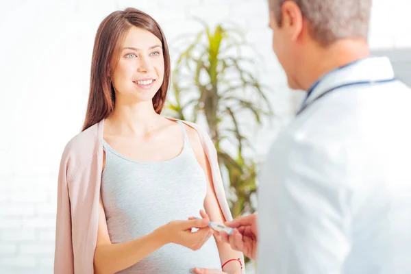 Beautiful pregnant woman giving thermometer to doctor — Stock Photo, Image