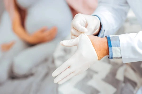 Primer plano del médico poniéndose guantes de goma —  Fotos de Stock