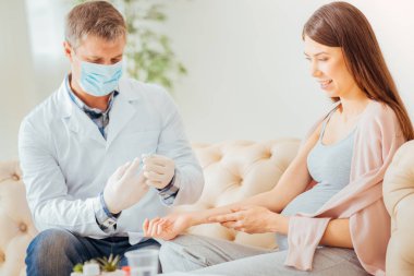 Şırınga tutarak ve üzerinde odaklanan dikkatli sakin doktor.