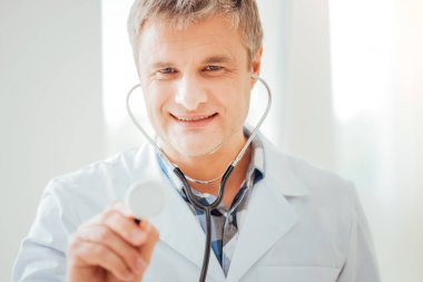 Onun statoscope kullanarak ve gülümseyen hoş memnun doktor.