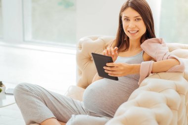 Oturma ve tablet kullanma memnun akıllı kadın.