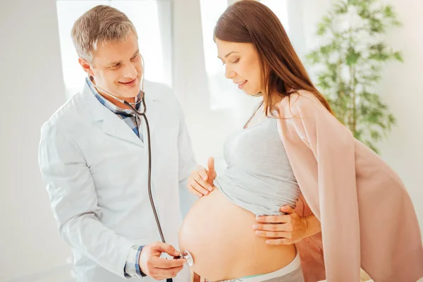 Radosny Kobieta w ciąży o badanie i patrząc na żołądek. — Zdjęcie stockowe