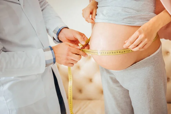 Young pleasant woman standing and measuring stomach. — Stock Photo, Image