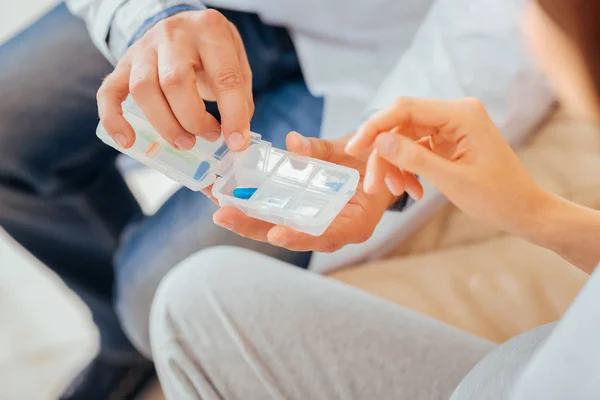 Calma médico cualificado sentado y sosteniendo píldoras . — Foto de Stock