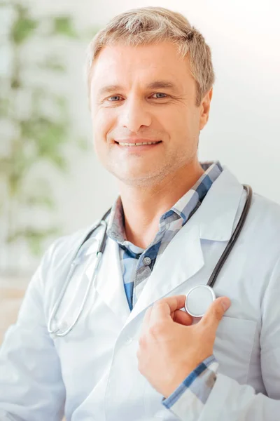 Ervaren vertrouwen medic raken aan de statoscope en glimlachen. — Stockfoto