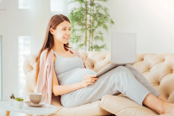 Cute gravid woman lying and using the laptop. — Stock Photo, Image