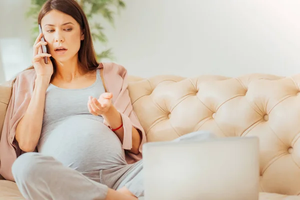 Serious occupied woman sitting and having phone conversation. — Stock Photo, Image