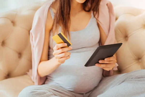 Smart pleasant woman sitting and holding card and tablet. — Stock Photo, Image