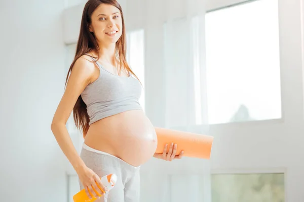 Cute pregnant woman standing and holding the rug. — Stock Photo, Image