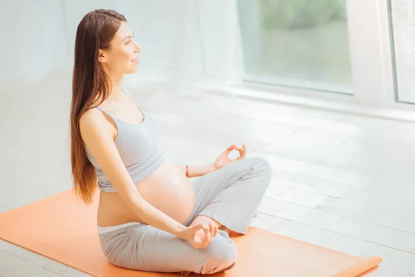 Pleasant young woman mediating on the floor and looking aside. — Stock Photo, Image