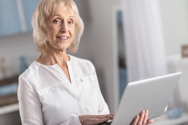Musing mature woman studying online