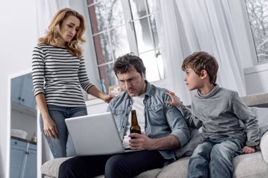 Ciddi adam yanında oturan onun aile üyeleri ise ekran bakıyor