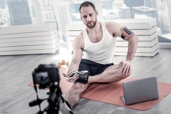 Konzentrierte männliche Bloggerin wärmt Beine — Stockfoto