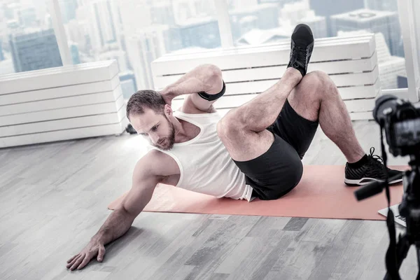 Konzentrierte männliche Bloggerin trainiert Bauchmuskeln — Stockfoto