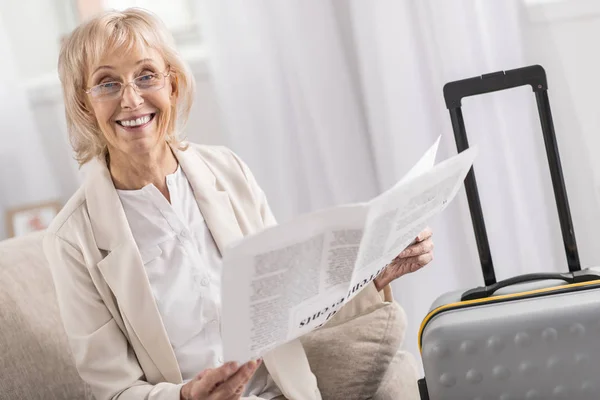 Pozytywne, Starsza kobieta, czytanie w pobliżu walizka — Zdjęcie stockowe