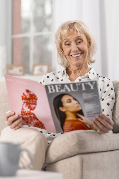 Happy mature woman flipping through magazine — Stock Photo, Image