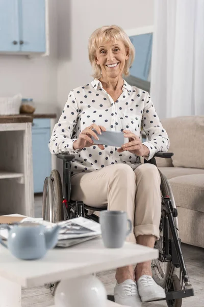 Mature disabled woman holding phone — Stock Photo, Image
